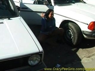 Crazy girl pissing behind a car